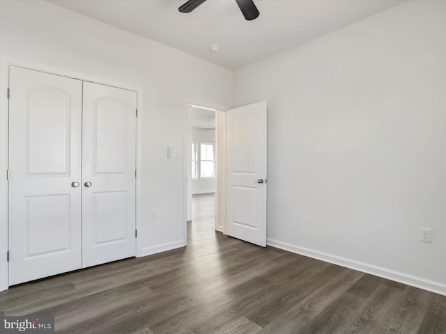 unfurnished bedroom with dark wood-style floors, baseboards, a closet, and a ceiling fan