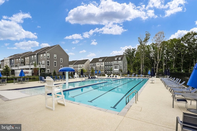 pool with a patio, fence, and a residential view