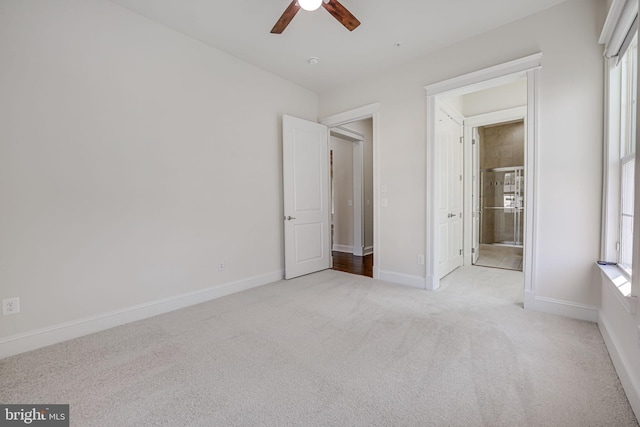 unfurnished bedroom with light carpet, ceiling fan, ensuite bathroom, and baseboards