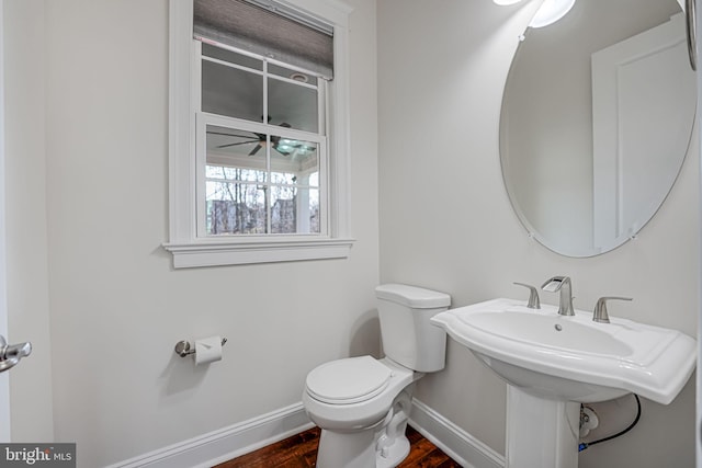 half bath with wood finished floors, toilet, and baseboards