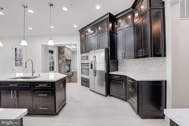 kitchen with stainless steel appliances, a sink, hanging light fixtures, decorative backsplash, and glass insert cabinets