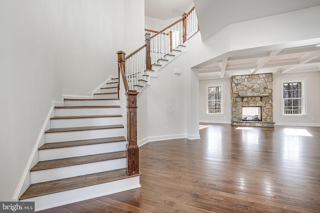 stairway featuring a fireplace, coffered ceiling, wood finished floors, and baseboards