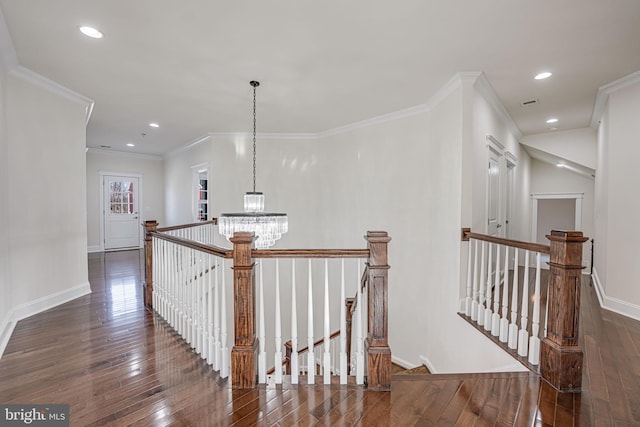 hall featuring an inviting chandelier, dark wood-type flooring, and an upstairs landing