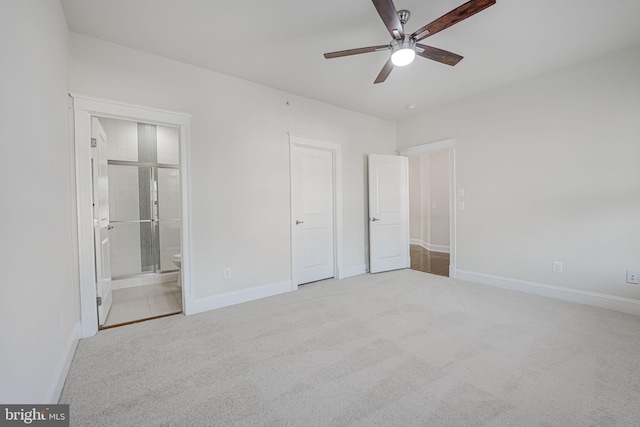 unfurnished bedroom featuring light carpet, connected bathroom, a ceiling fan, and baseboards