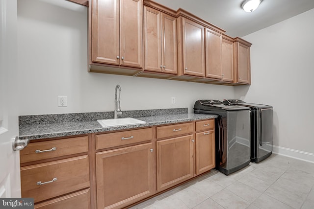 clothes washing area featuring washing machine and clothes dryer, light tile patterned floors, cabinet space, a sink, and baseboards