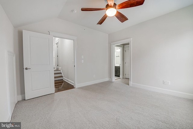 unfurnished bedroom with lofted ceiling, light carpet, ceiling fan, and baseboards