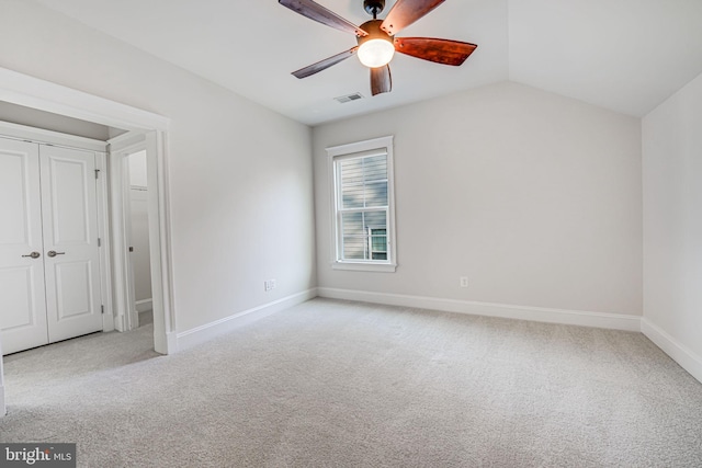 unfurnished bedroom with light carpet, visible vents, baseboards, a ceiling fan, and vaulted ceiling