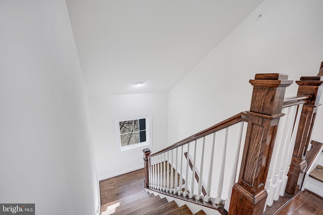 stairs featuring baseboards, vaulted ceiling, and wood finished floors