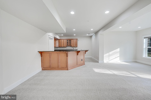 kitchen featuring a peninsula, dark countertops, glass insert cabinets, and open floor plan