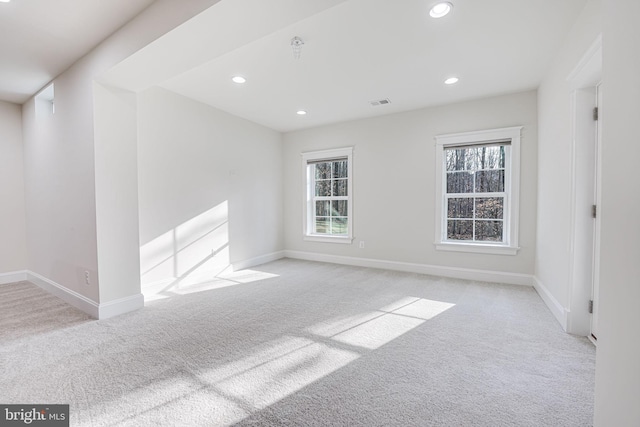 empty room featuring recessed lighting, light colored carpet, and baseboards