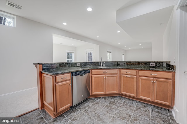 kitchen featuring a peninsula, dark stone countertops, brown cabinetry, and dishwasher