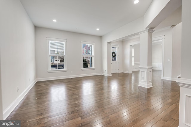 unfurnished living room featuring recessed lighting, dark wood-style flooring, decorative columns, and baseboards