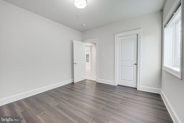 unfurnished bedroom with dark wood-style flooring and baseboards