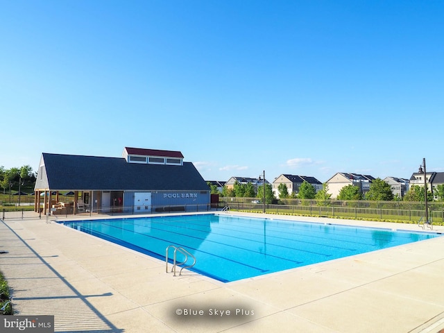 community pool with a patio area, fence, and a residential view