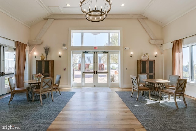 dining room featuring a chandelier, high vaulted ceiling, wood finished floors, french doors, and ornamental molding