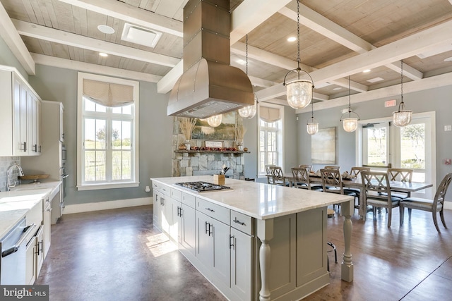 kitchen with white cabinets, a kitchen island, light stone counters, decorative light fixtures, and island exhaust hood