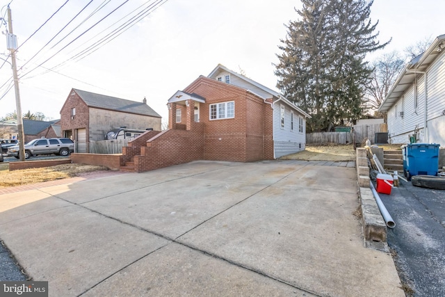 view of side of home with fence, central AC, and brick siding