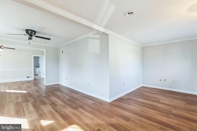 unfurnished room with crown molding, visible vents, ceiling fan, wood finished floors, and baseboards