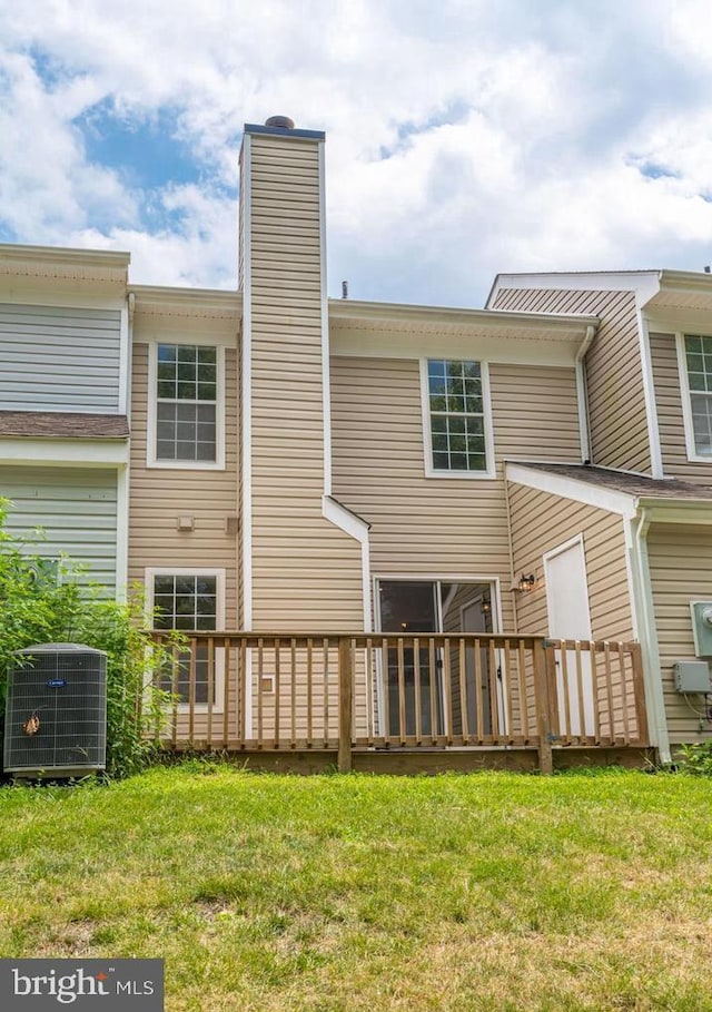 rear view of property featuring a deck, cooling unit, a lawn, and a chimney