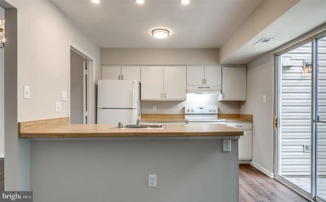 kitchen featuring white appliances, visible vents, under cabinet range hood, white cabinetry, and a sink