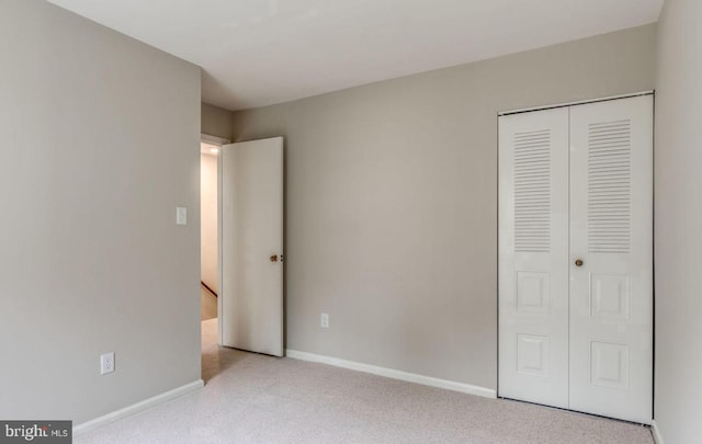 unfurnished bedroom featuring a closet, baseboards, and carpet flooring