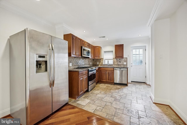 kitchen featuring baseboards, ornamental molding, stainless steel appliances, stone tile flooring, and backsplash