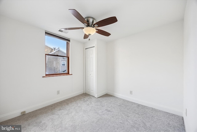 carpeted empty room with a ceiling fan, visible vents, and baseboards