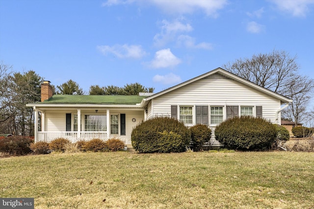 ranch-style home featuring covered porch, a chimney, and a front yard