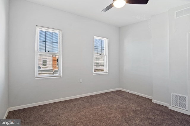 empty room featuring dark colored carpet, visible vents, and baseboards