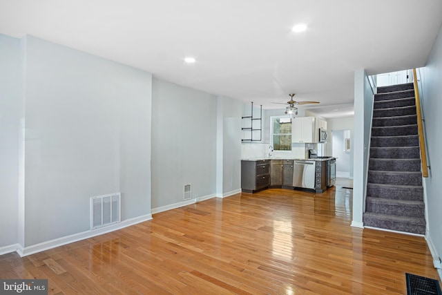 unfurnished living room with light wood-type flooring, stairs, and visible vents