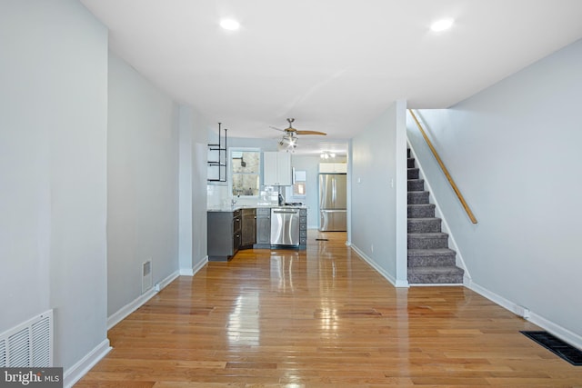 unfurnished living room with visible vents, light wood finished floors, and stairs