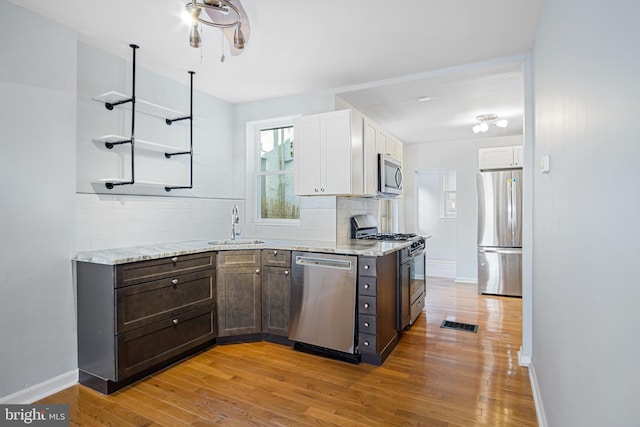 kitchen featuring dark brown cabinets, appliances with stainless steel finishes, white cabinetry, and tasteful backsplash