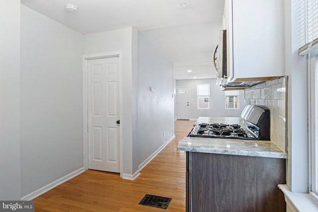 kitchen featuring visible vents, light wood-type flooring, gas range, and white cabinets