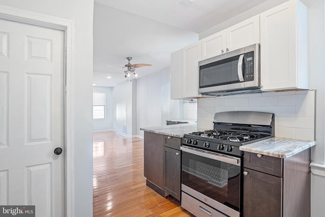 kitchen with a ceiling fan, white cabinets, appliances with stainless steel finishes, decorative backsplash, and light wood finished floors