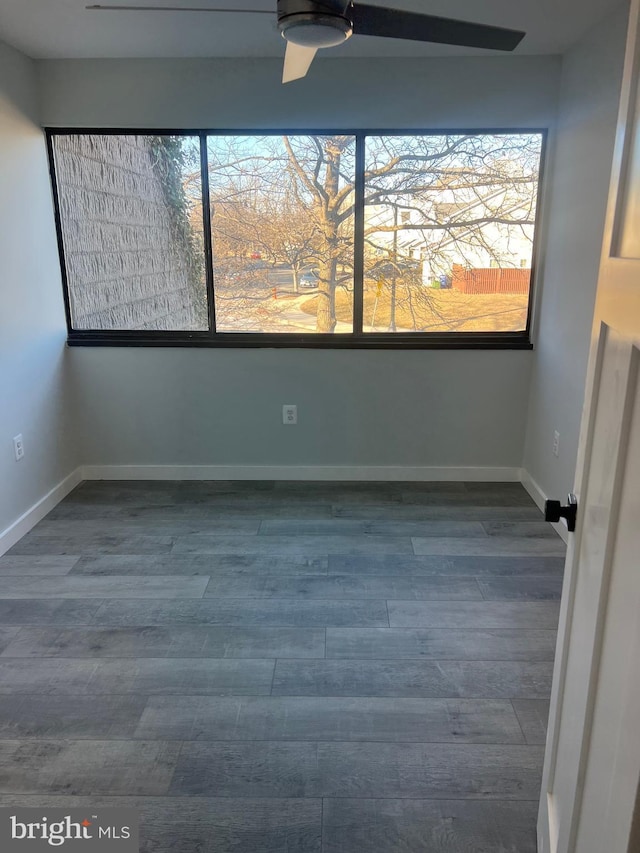 spare room featuring baseboards and dark wood finished floors