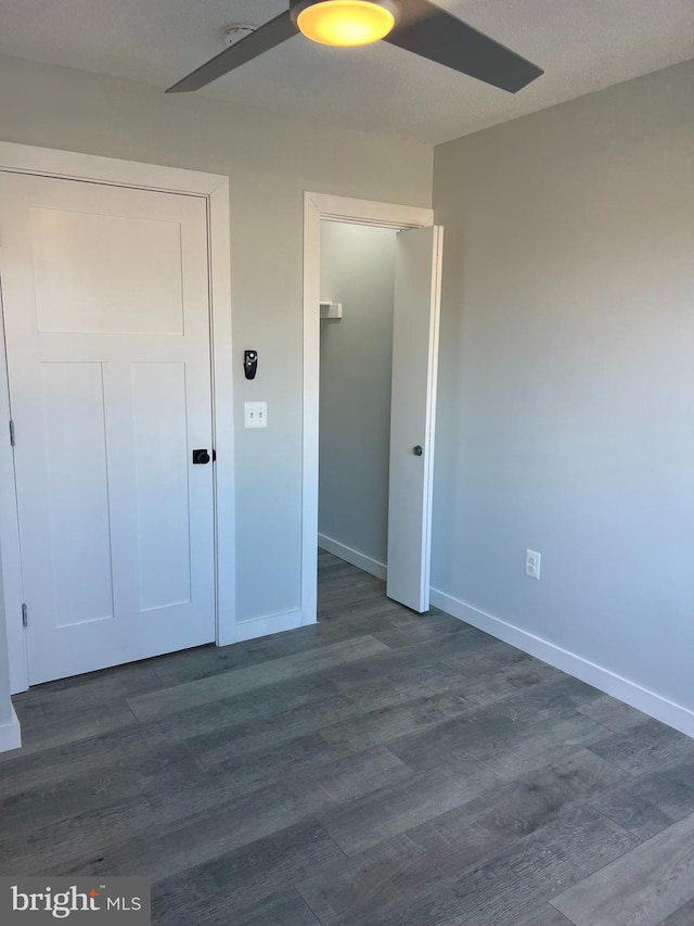 unfurnished bedroom with dark wood finished floors, baseboards, and ceiling fan