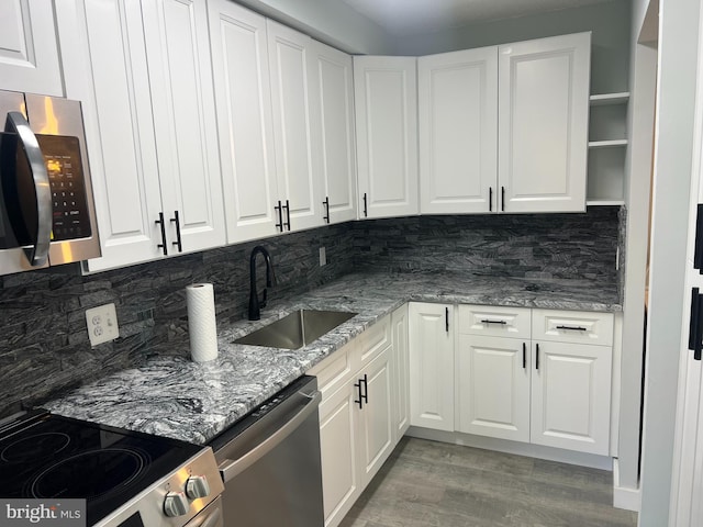 kitchen with stainless steel appliances, open shelves, a sink, and white cabinets