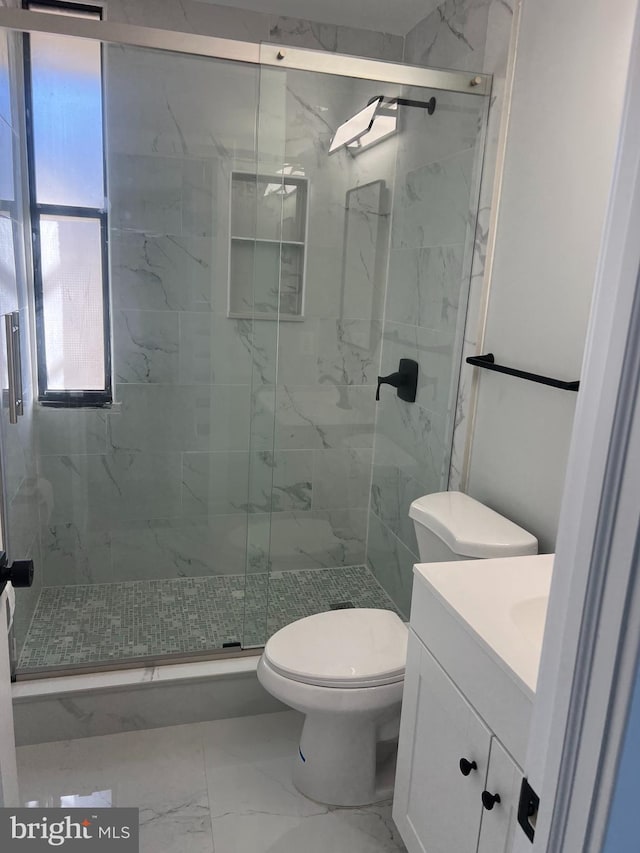 bathroom featuring toilet, marble finish floor, a shower stall, and vanity