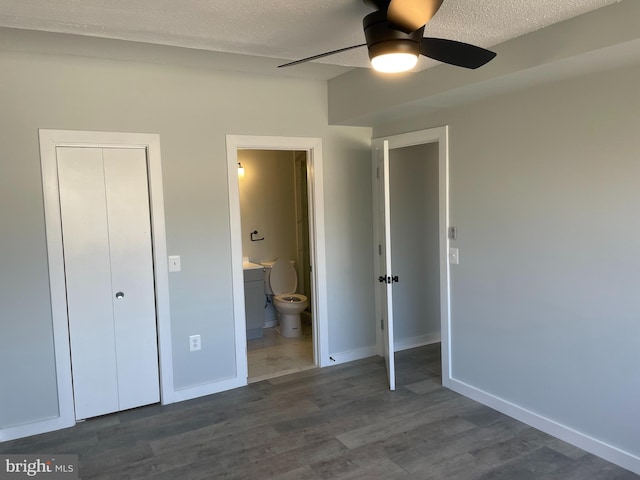 unfurnished bedroom featuring a closet, a textured ceiling, baseboards, and dark wood-type flooring