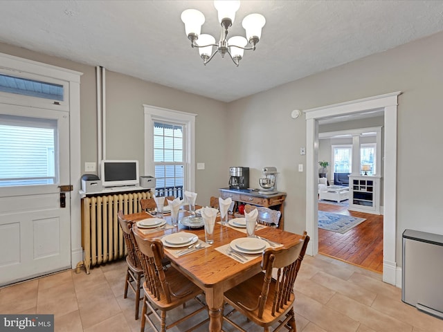 dining room featuring radiator, a healthy amount of sunlight, a notable chandelier, and light tile patterned flooring