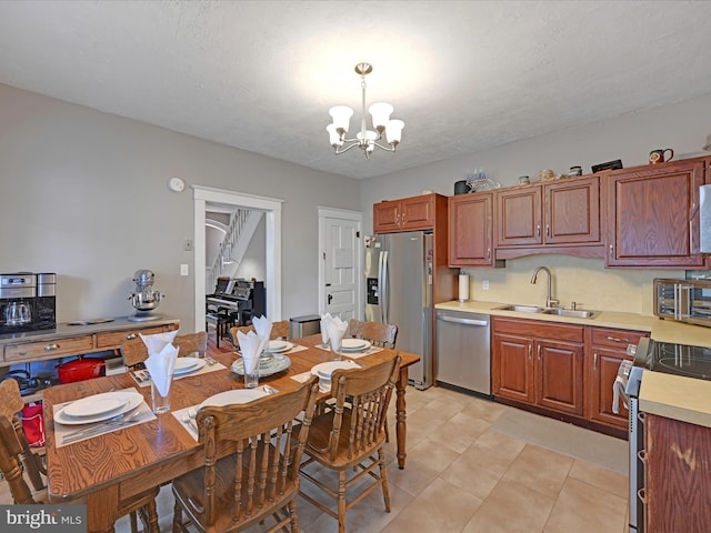 kitchen featuring pendant lighting, a notable chandelier, stainless steel appliances, light countertops, and a sink