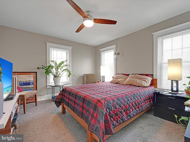 carpeted bedroom with radiator heating unit, a ceiling fan, and baseboards