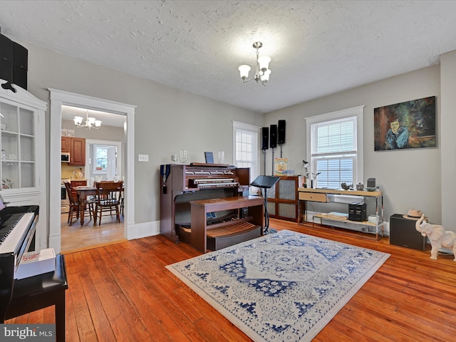 interior space with an inviting chandelier, a textured ceiling, baseboards, and wood finished floors