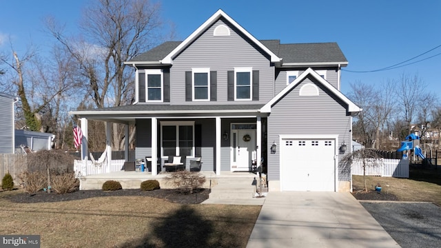 traditional-style house with a garage, driveway, covered porch, fence, and a front lawn