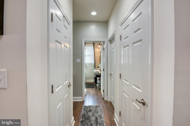 hallway featuring dark wood-style flooring and baseboards