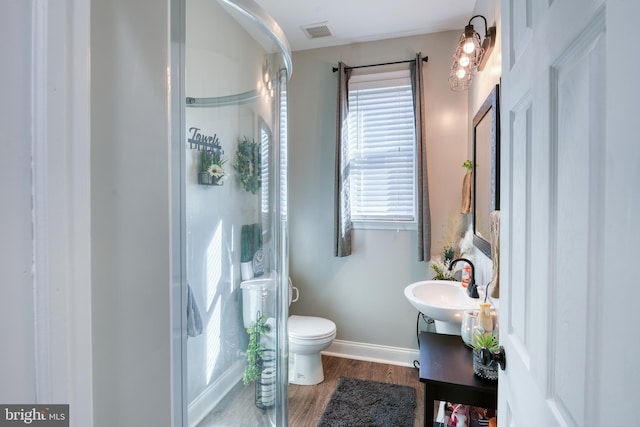 bathroom with a stall shower, visible vents, toilet, and wood finished floors