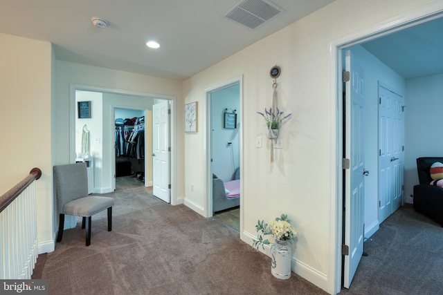 hallway with carpet floors, recessed lighting, visible vents, and baseboards