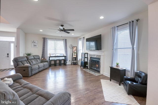 living area featuring a high end fireplace, a healthy amount of sunlight, light wood finished floors, and recessed lighting