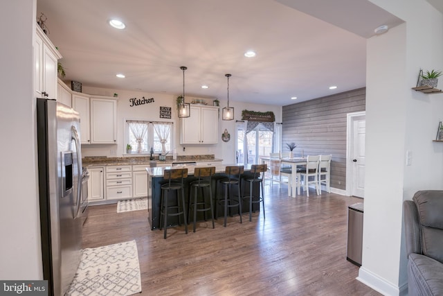 kitchen featuring a breakfast bar area, a kitchen island, white cabinetry, hanging light fixtures, and stainless steel fridge