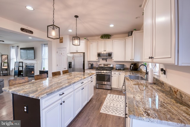 kitchen featuring stainless steel appliances, a center island, a sink, and light stone counters